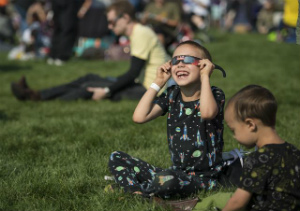 A boy watches the total solar eclipse through protective glasses